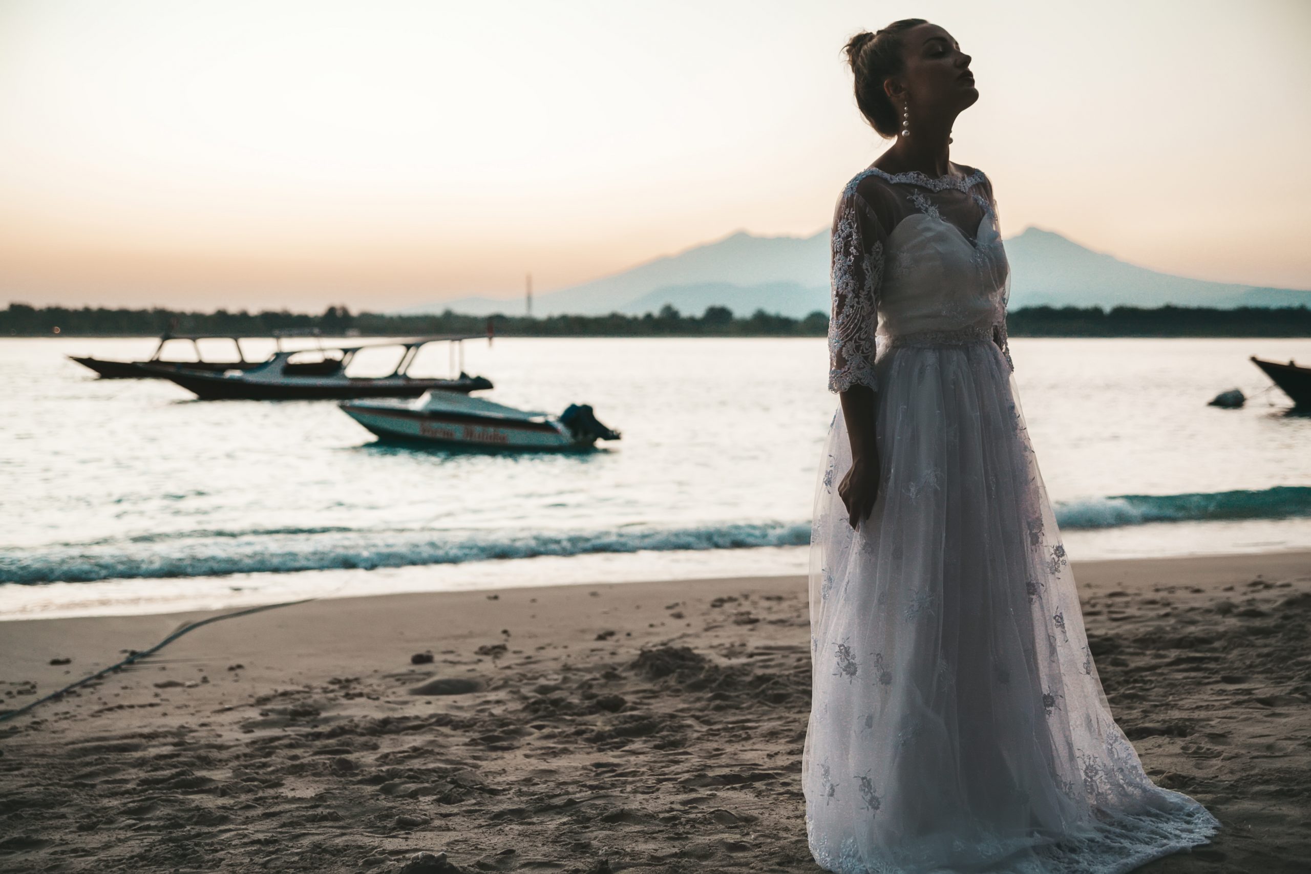 Portrait of  beautiful bride posing on the beach behind sea at sunset